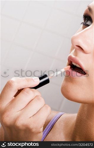Close-up of a young woman applying lipstick on her lips