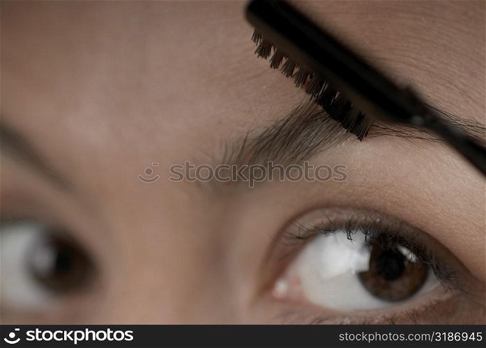 Close-up of a young woman applying make-up on her eyebrow
