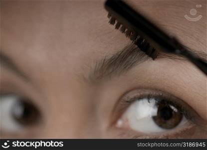 Close-up of a young woman applying make-up on her eyebrow