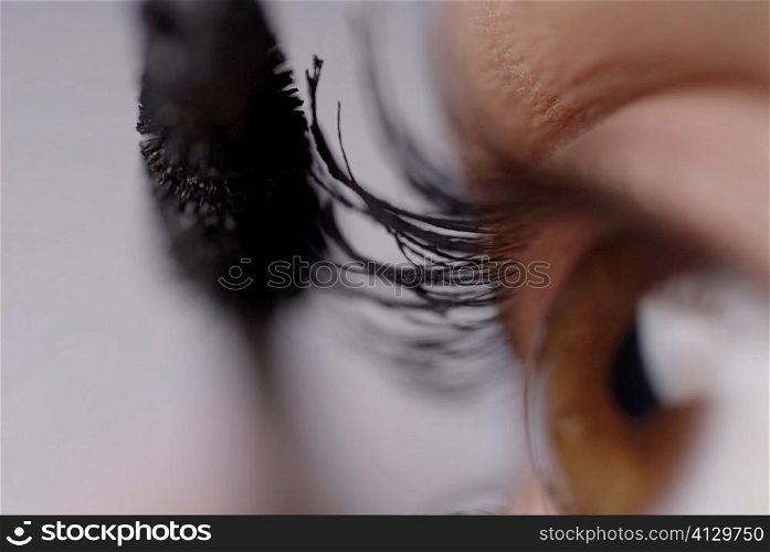 Close-up of a young woman applying mascara