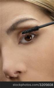Close-up of a young woman applying mascara on her eyelashes