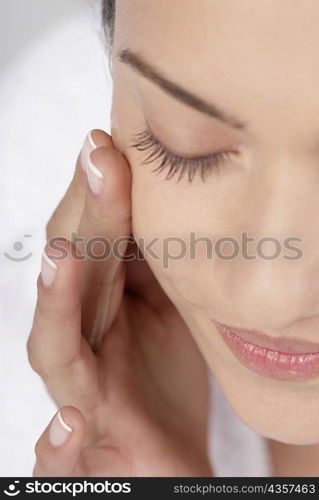 Close-up of a young woman applying moisturizer on her cheeks