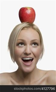 Close-up of a young woman balancing an apple on her head
