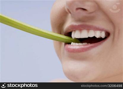 Close-up of a young woman biting a celery stick
