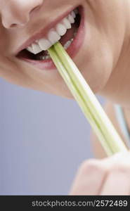 Close-up of a young woman biting celery sticks