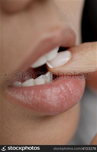 Close-up of a young woman biting her finger