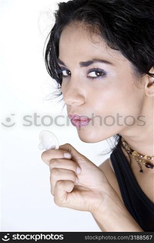 Close-up of a young woman blowing a condom