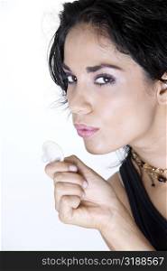 Close-up of a young woman blowing a condom