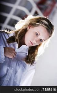 Close-up of a young woman buttoning her shirt