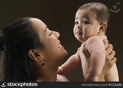 Close-up of a young woman carrying her son and smiling