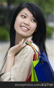 Close-up of a young woman carrying shopping bags and smiling
