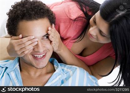 Close-up of a young woman covering a young man&acute;s eyes