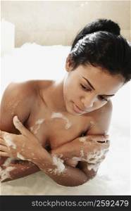 Close-up of a young woman covering her breasts in a bathtub