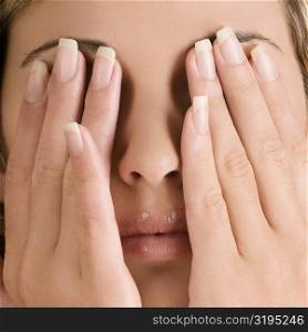 Close-up of a young woman covering her eyes with her hands