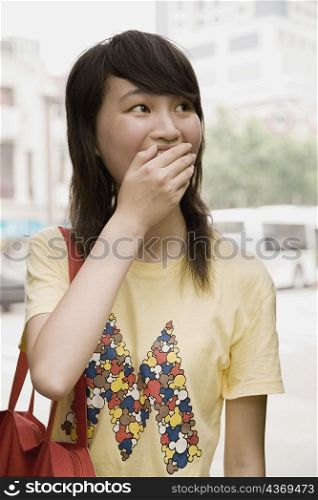 Close-up of a young woman covering her mouth with her hand