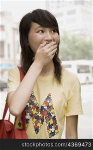 Close-up of a young woman covering her mouth with her hand