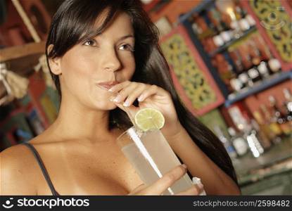 Close-up of a young woman drinking a glass of lemonade