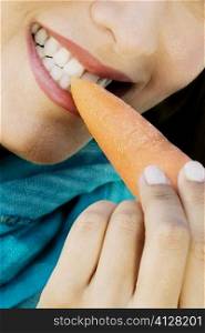 Close-up of a young woman eating a carrot