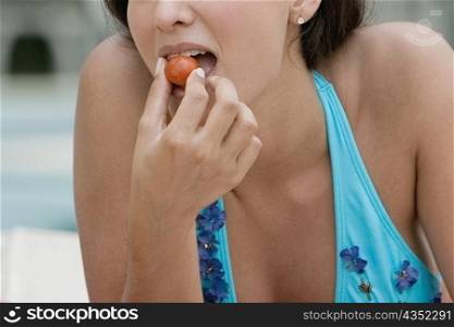 Close-up of a young woman eating a cherry tomato