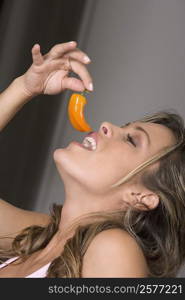 Close-up of a young woman eating a chili pepper