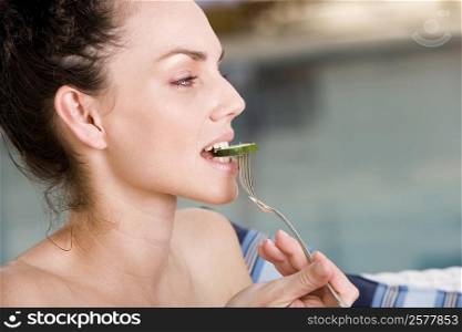Close-up of a young woman eating a cucumber slice