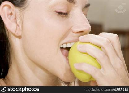 Close-up of a young woman eating a green apple