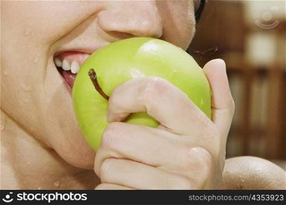 Close-up of a young woman eating a green apple