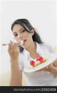Close-up of a young woman eating a pastry with a fork