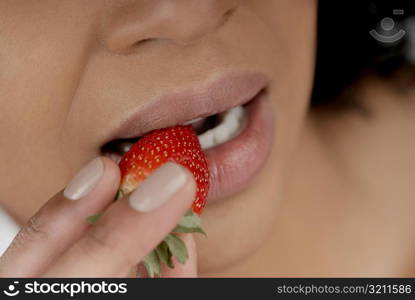 Close-up of a young woman eating a strawberry