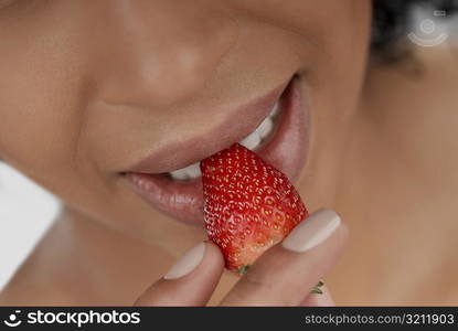 Close-up of a young woman eating a strawberry