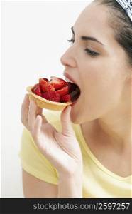 Close-up of a young woman eating a strawberry tart