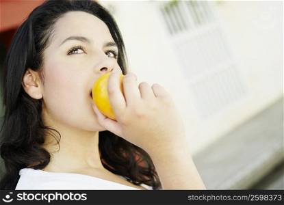 Close-up of a young woman eating an orange