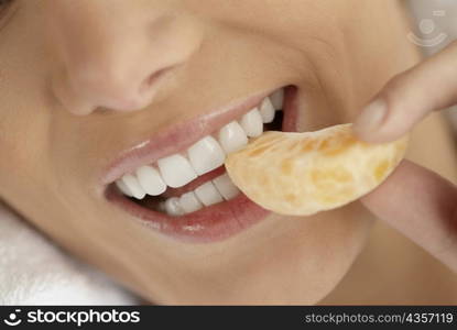 Close-up of a young woman eating an orange