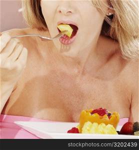 Close-up of a young woman eating fruit salad with a fork