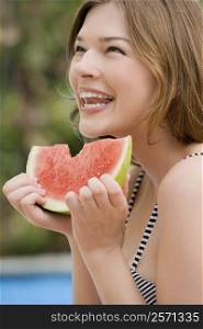 Close-up of a young woman eating watermelon and smiling