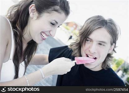 Close-up of a young woman feeding an ice-cream to a teenage boy