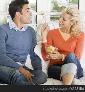 Close-up of a young woman feeding salad to a young man