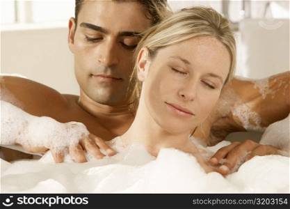 Close-up of a young woman getting a massage from a young man in a bubble bath