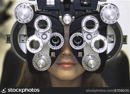 Close-up of a young woman getting an eye test with a phoropter