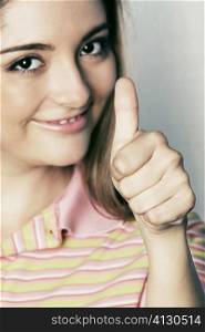Close-up of a young woman giving a thumbs up sign