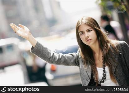 Close-up of a young woman hailing a taxi