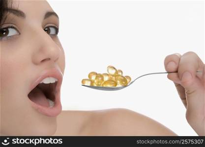 Close-up of a young woman having pills from a spoon