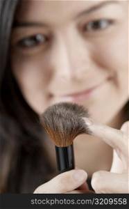 Close-up of a young woman holding a blush brush