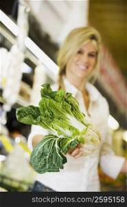 Close-up of a young woman holding a bok choy in a supermarket