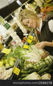 Close-up of a young woman holding a bok choy in a supermarket