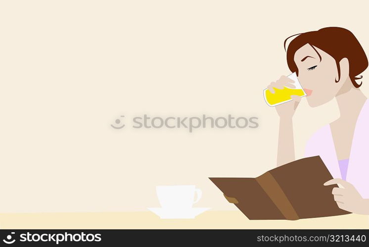 Close-up of a young woman holding a book and drinking juice