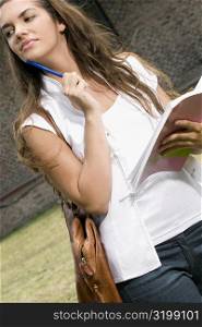 Close-up of a young woman holding a book and looking away