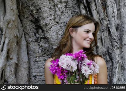 Close-up of a young woman holding a bouquet of flowers and looking away