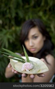 Close-up of a young woman holding a bowl of herb