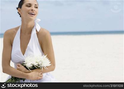 Close-up of a young woman holding a bunch of flowers on the beach